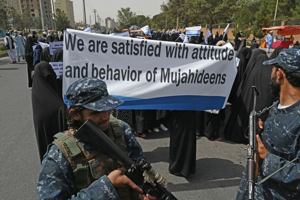 An armed Taliban fighters escort veiled women as they march during a pro-Taliban rally outside the Shaheed Rabbani Education University in Kabul on September 11, 2021. (Photo by Aamir QURESHI / AFP) (Photo by AAMIR QURESHI/AFP via Getty Images)