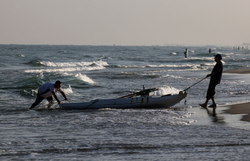 Palestinian fishermen pull a boat along a beach at the Mediterranean Sea in Khan Yunis, in the southern Gaza Strip, on September 22, 2021. - Israel said on September 1 it will expand Gaza's fishing zone, increase its water supply and allow more Palestinian traders and goods to enter Israel, even though violence has persisted on the border. (Photo by SAID KHATIB / AFP) (Photo by SAID KHATIB/AFP via Getty Images)